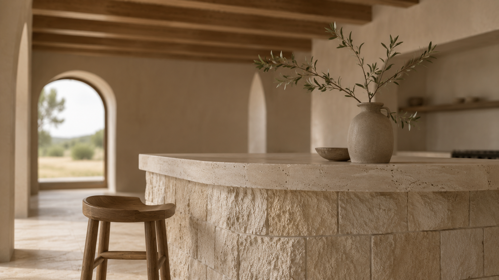 A textured travertine kitchen island beneath exposed timber beams.